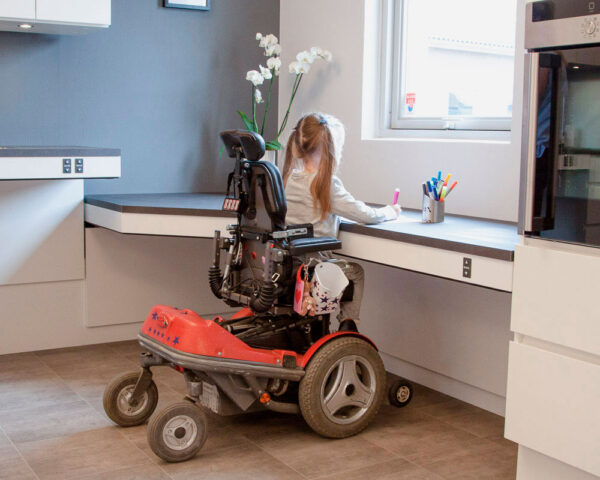 Girl in a wheelchair at a kitchen table